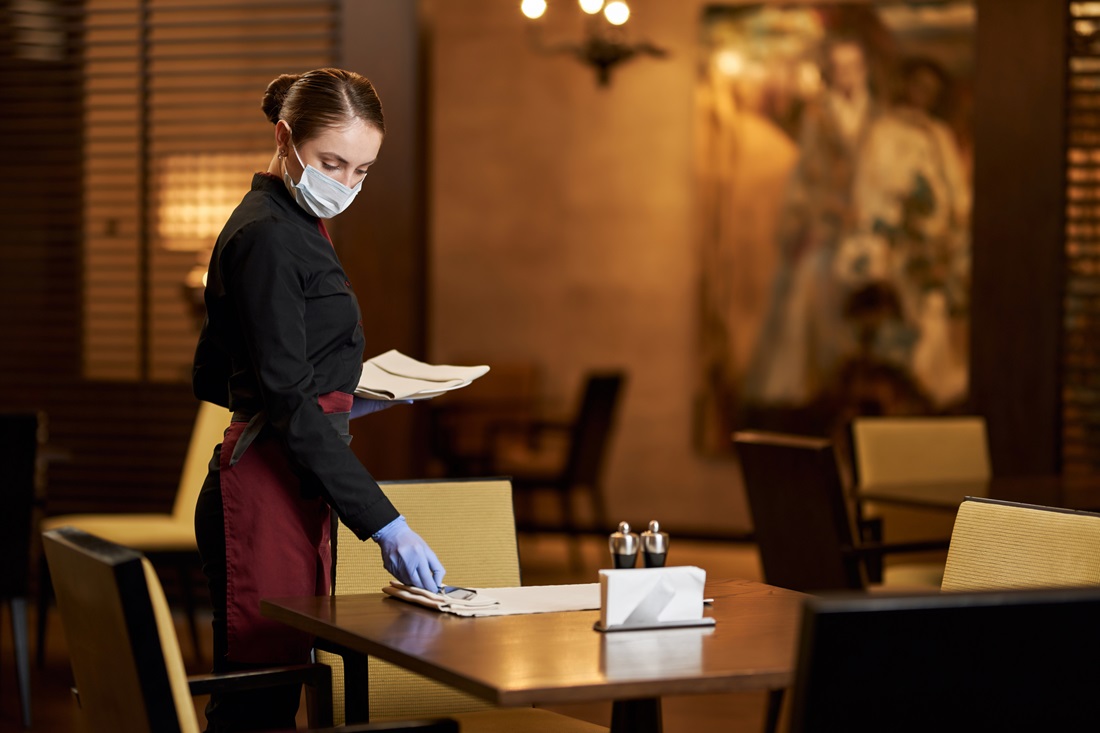 Hospitality trainee setting up a formal dining table for service practice